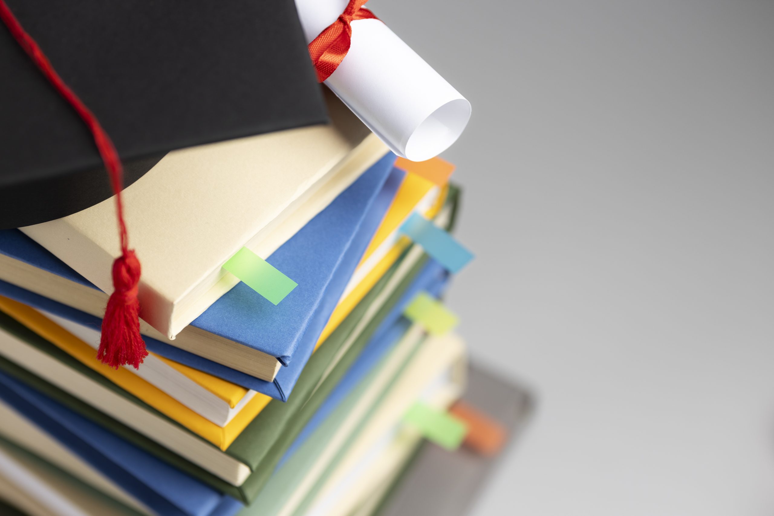 alto-angulo-de-libros-apilados-una-gorra-de-graduacion-y-un-diploma-para-el-dia-de-la-educacion